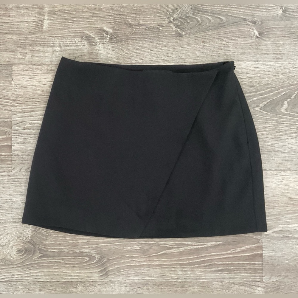 Black mini skirt with apron front slit detail.